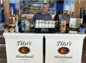 a man behind a counter with bottles of liquor