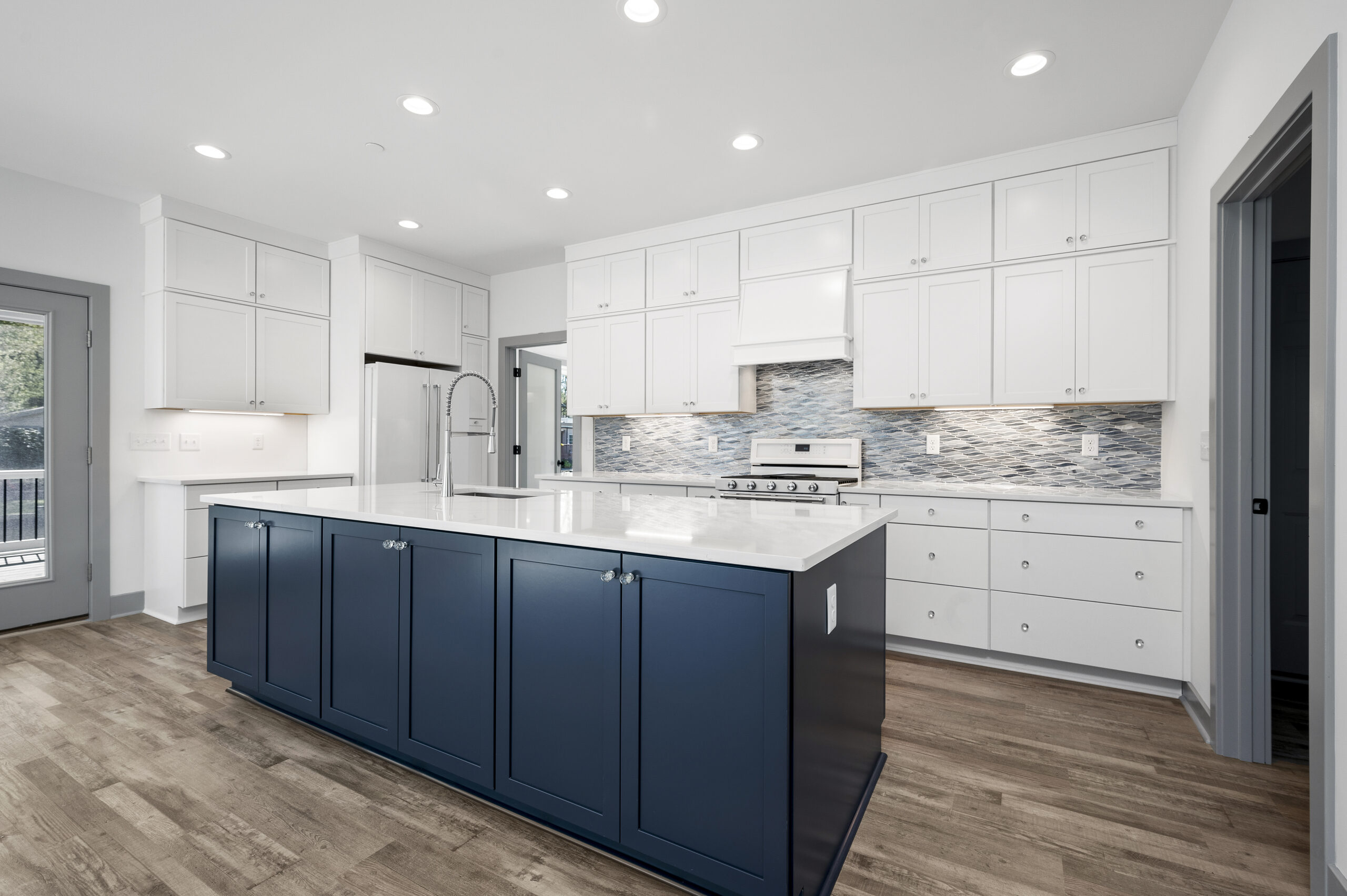 a large kitchen with white cabinets and a blue island