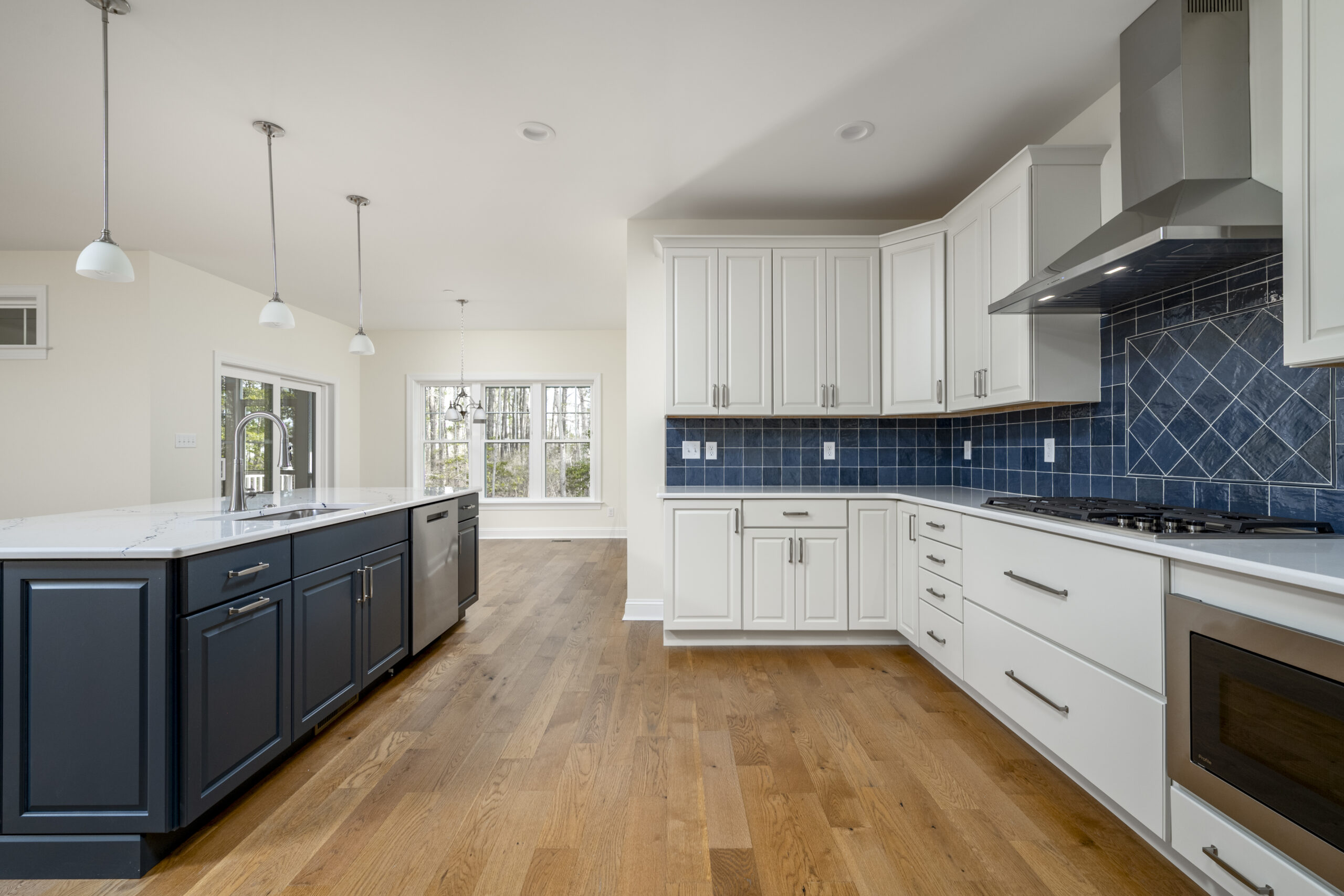a large kitchen with white cabinets and blue backsplash