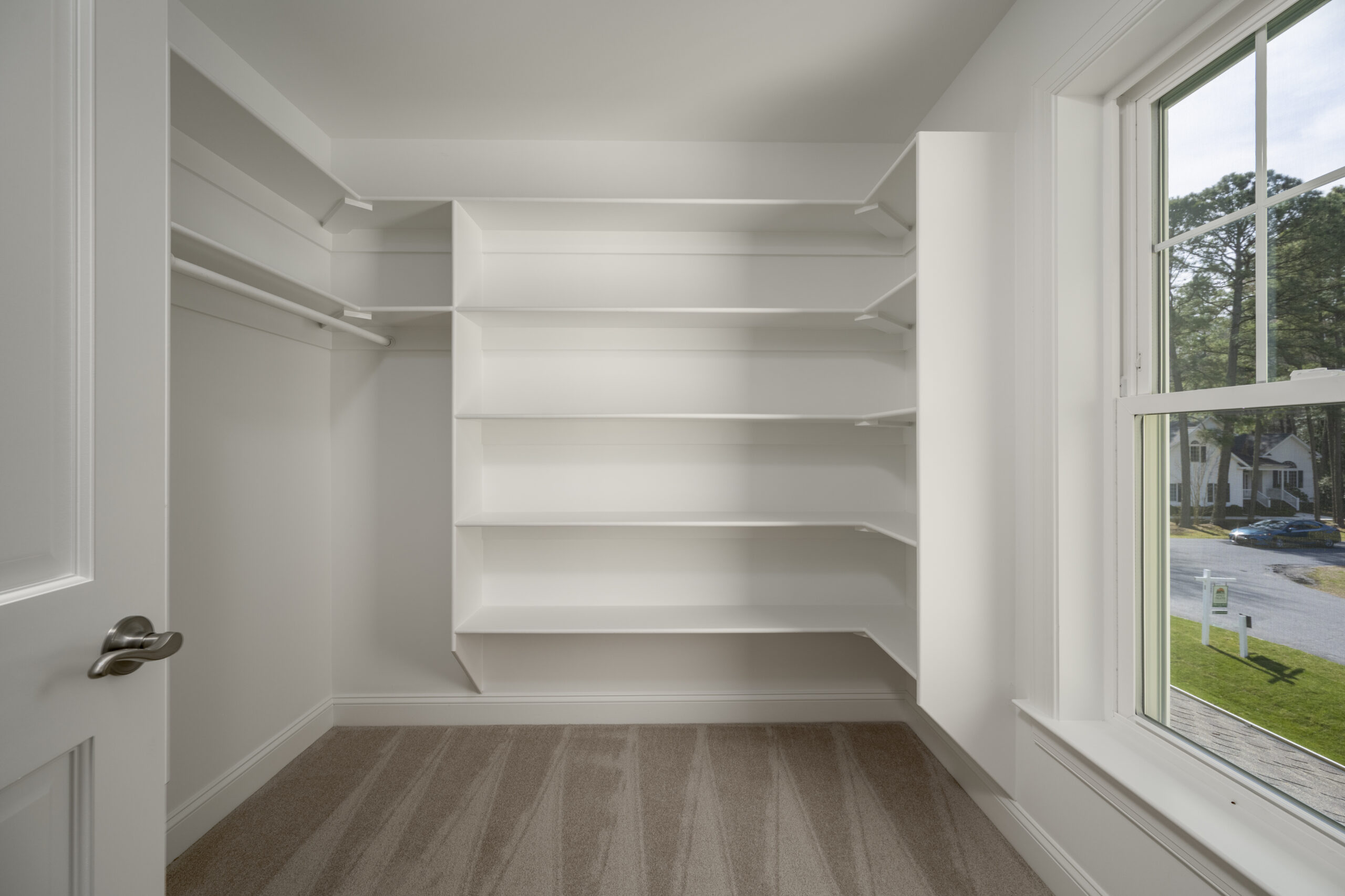 an empty walk in closet with white shelves