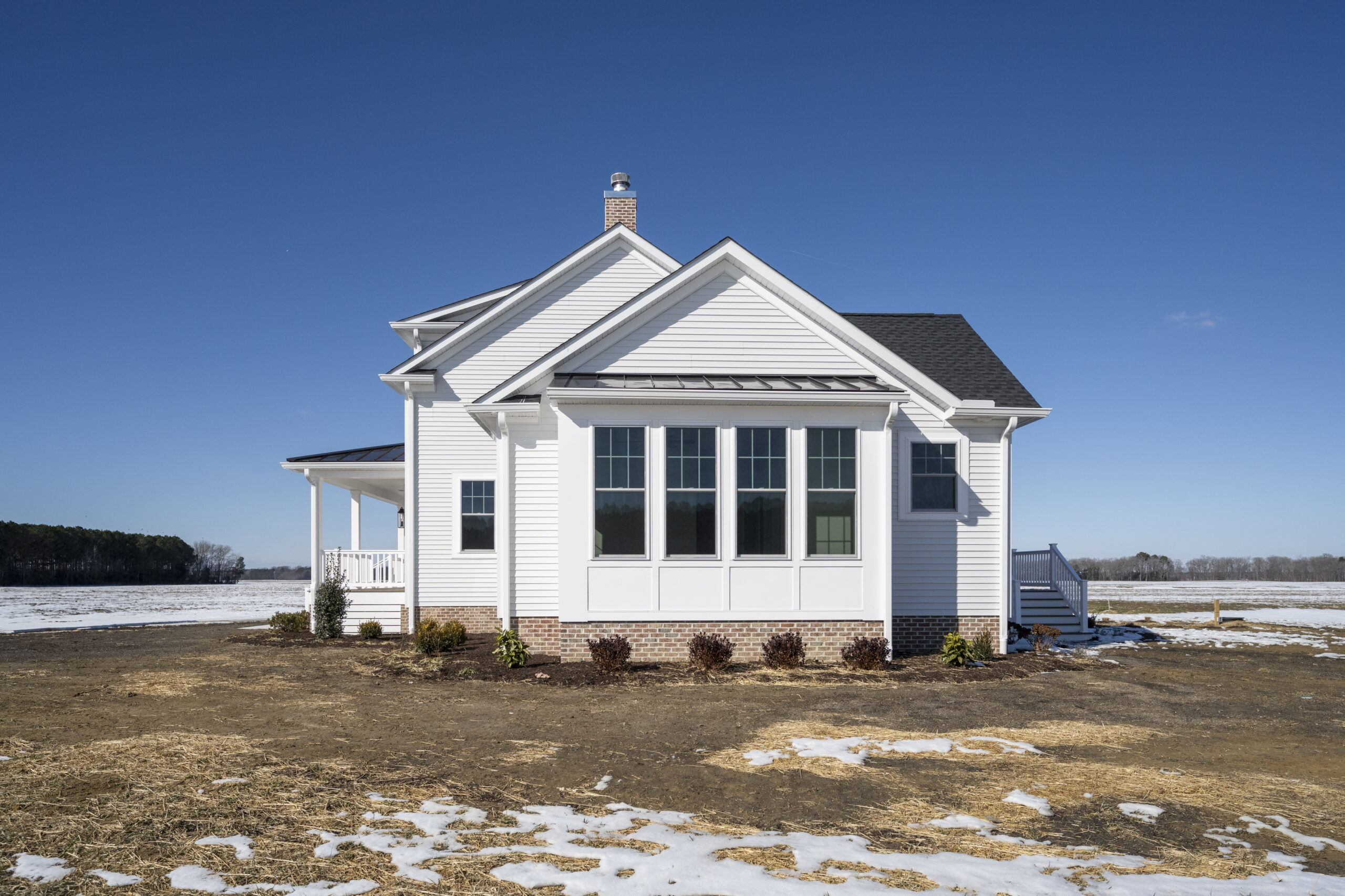 a small white house sitting on top of a snow covered field