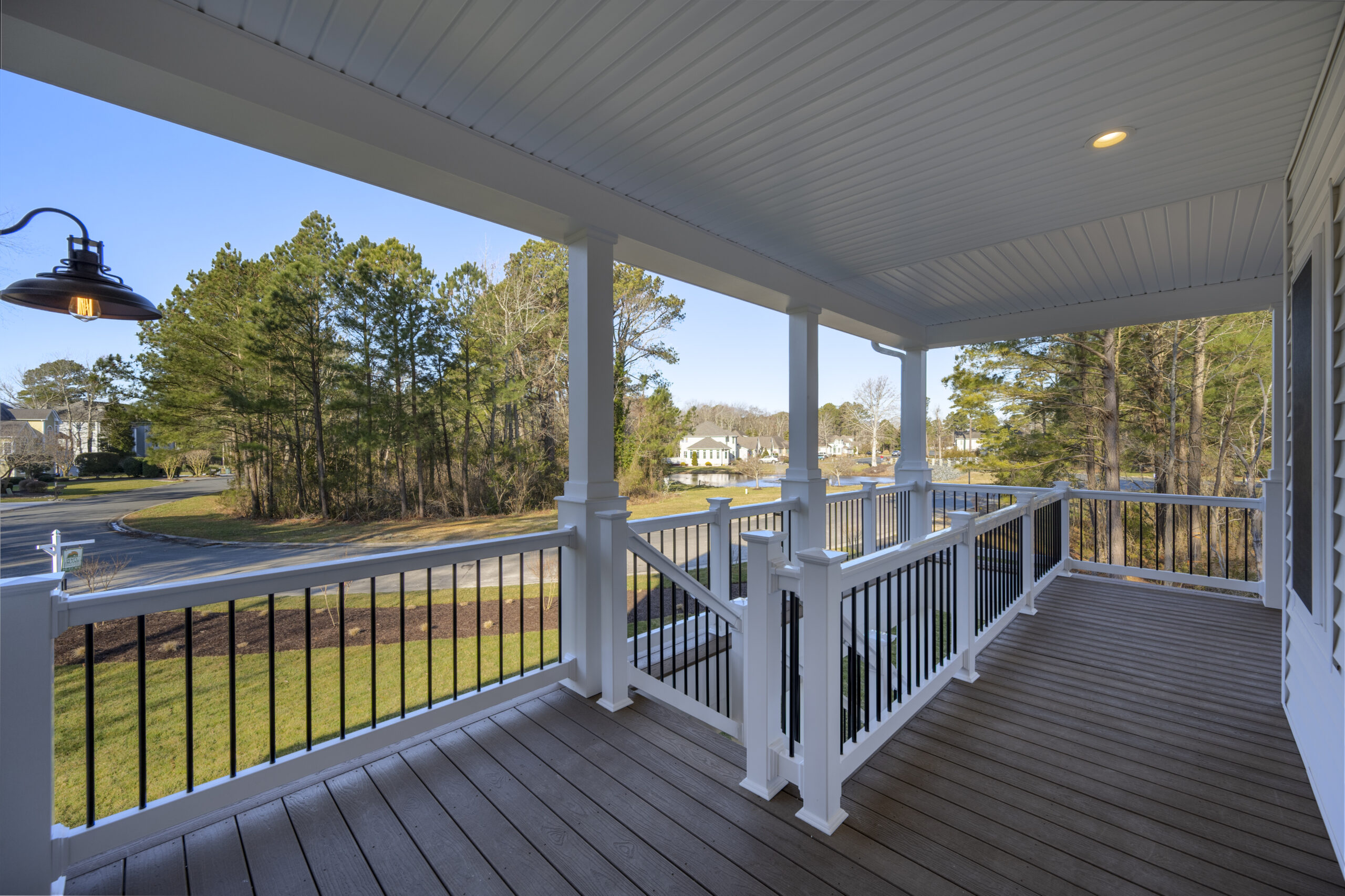 a porch with white railings and a lamp on the side of it