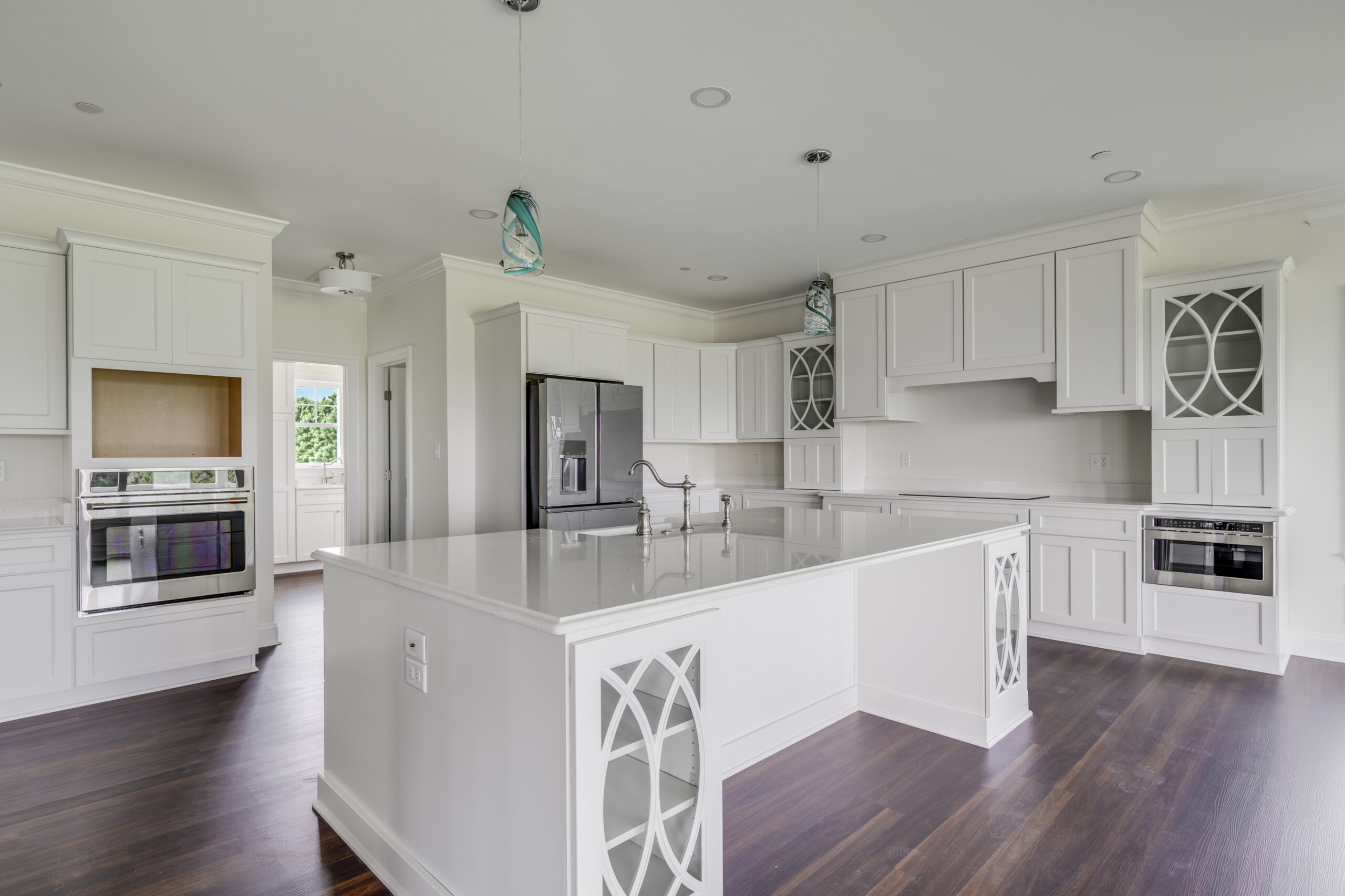 a large kitchen with white cabinets and wood floors
