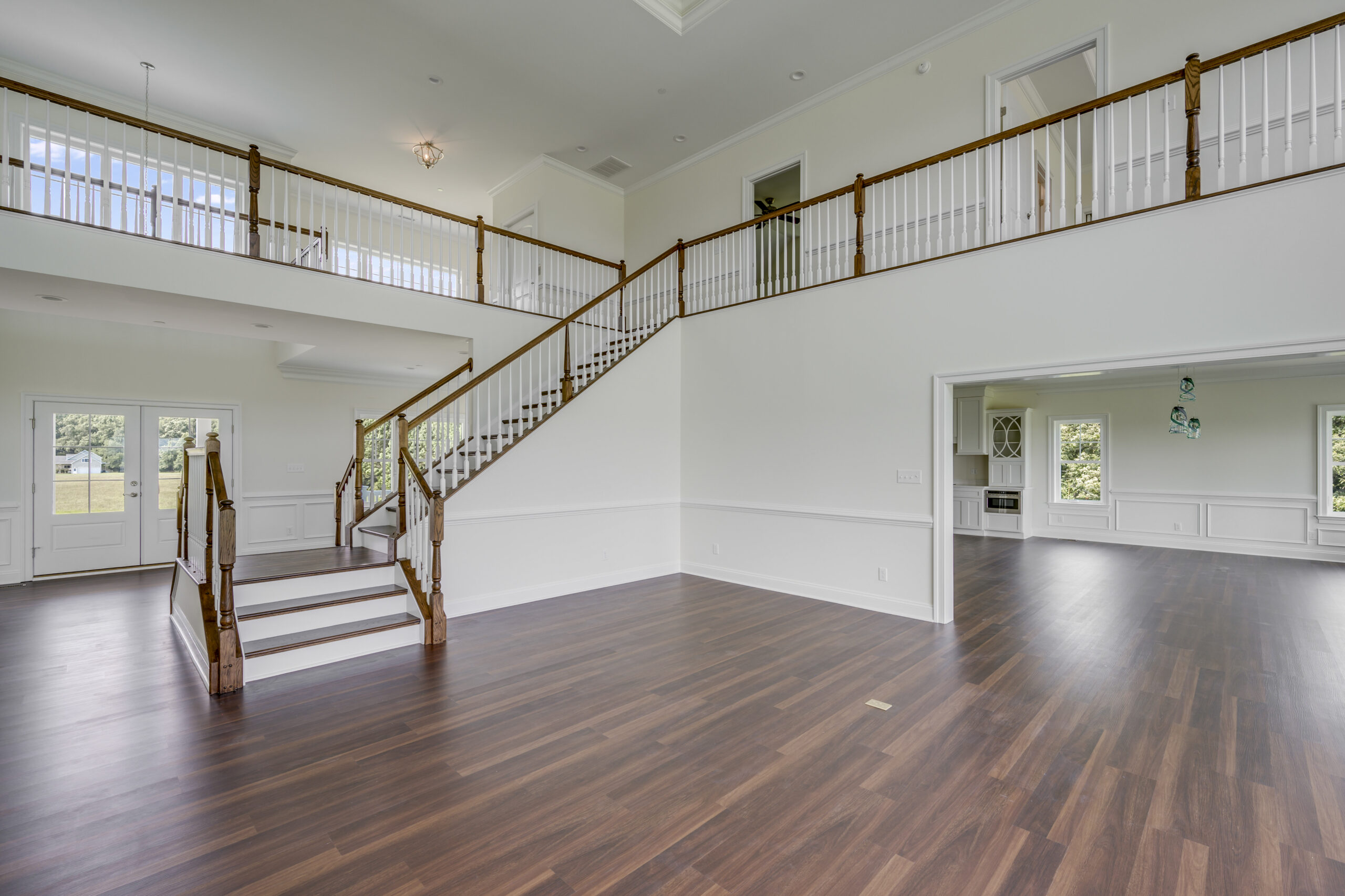 a large empty room with a staircase and hard wood floors