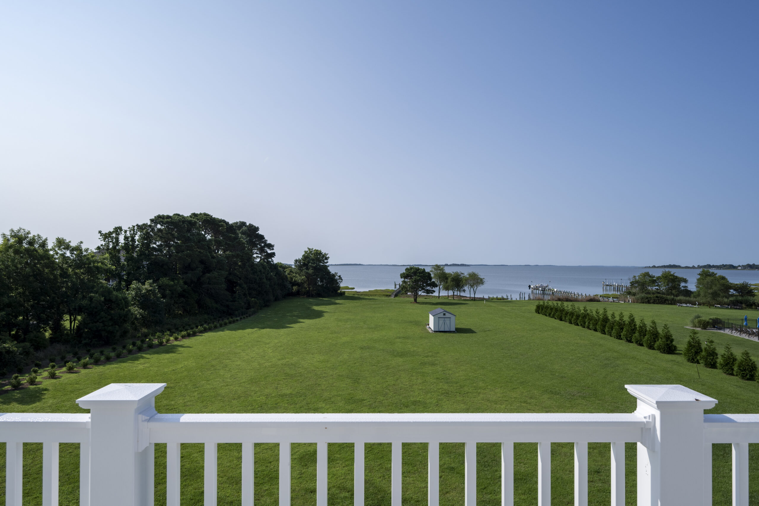 a white fence in front of a grassy field