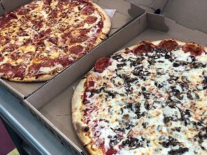 two large pizzas sitting in boxes on a table