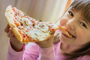 a young girl eating a slice of pizza
