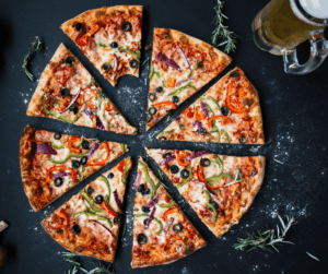 a sliced pizza on a table with a glass of beer