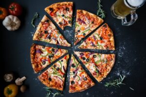 a sliced pizza sitting on top of a table next to a glass of beer