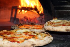 two pizzas sitting in front of an open oven