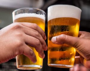 a couple of people that are holding some glasses of beer