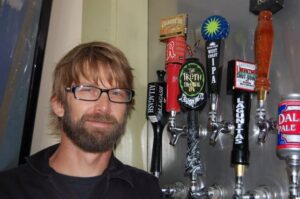 a man standing in front of a wall of beer taps