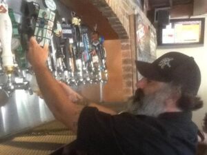 a man with a beard and a beard is fixing a beer at a bar