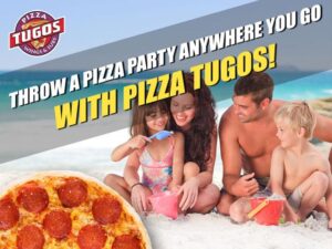 a group of people sitting around a pizza on the beach