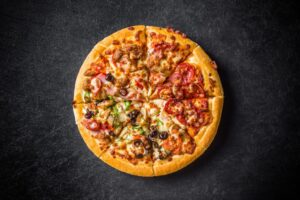 a pizza with various toppings on a black surface