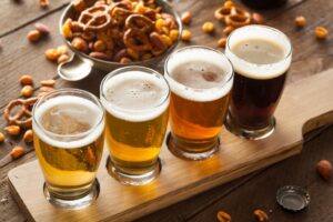 a wooden table topped with glasses of beer and nuts