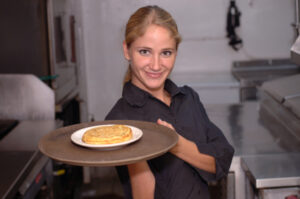 a woman holding a plate of food in a kitchen