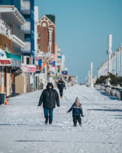 a man and a child walking down a snow covered street