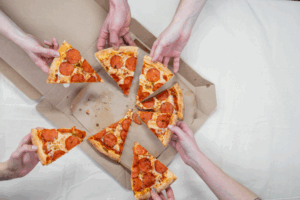 a group of people holding slices of pizza