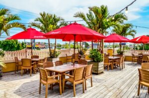 tables and chairs with red umbrellas on a deck