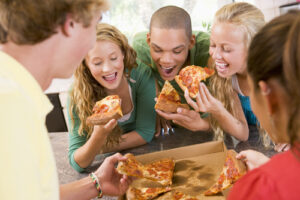 a group of young people eating pizza together