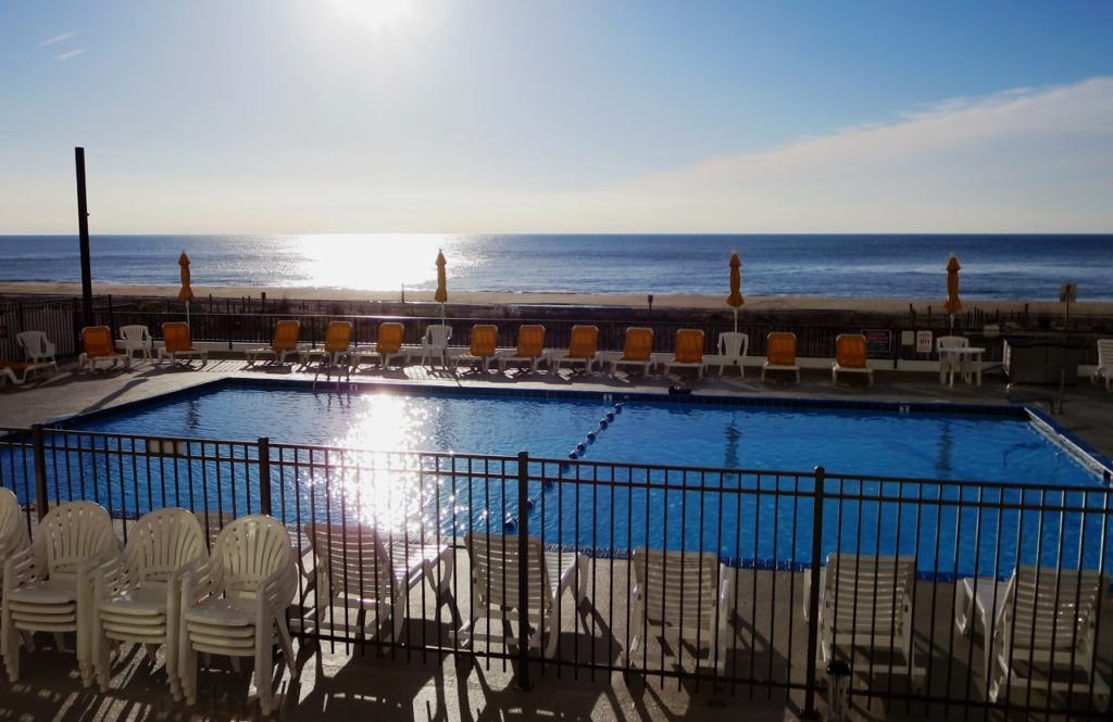 outdoor pool with lawn chairs and ocean view