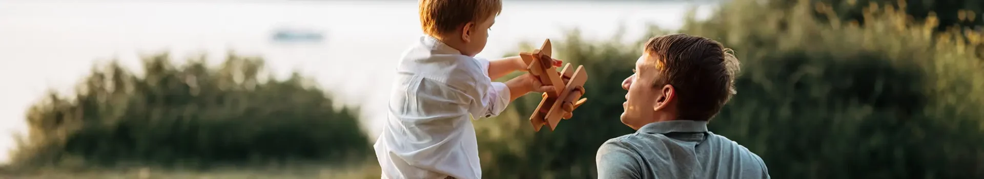 father and son outside with wooden toy plane