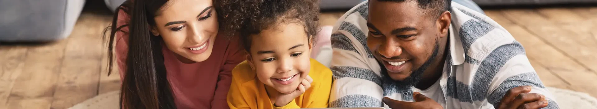 Three family members laying on the floor looking at something
