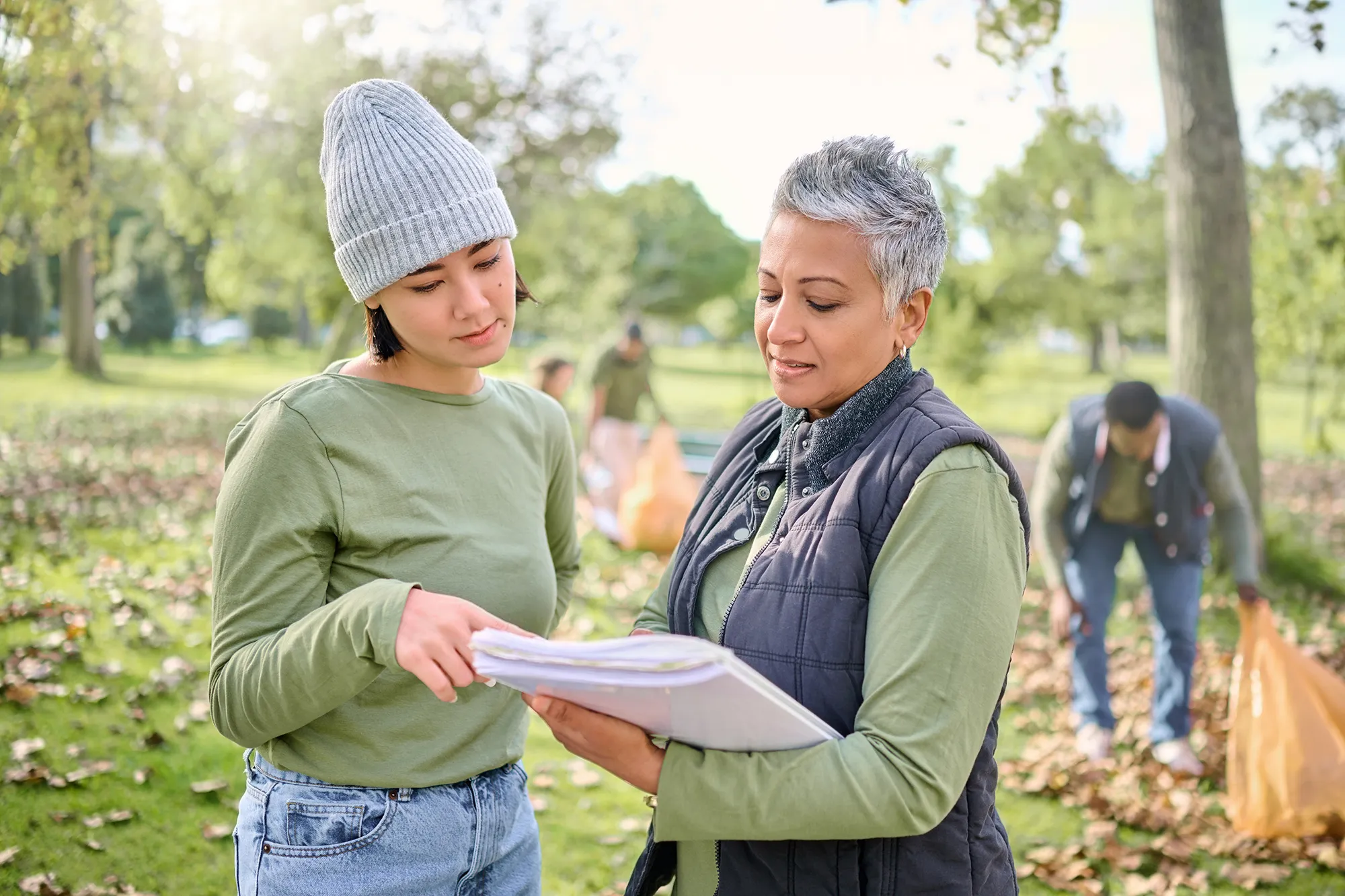 two women looking at notebook outside