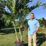 a man standing next to a palm tree