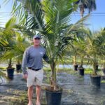 a man standing next to a palm tree