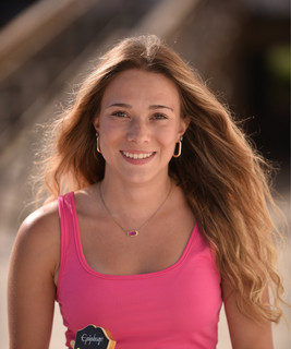 a woman in a pink tank top holding a yellow frisbee