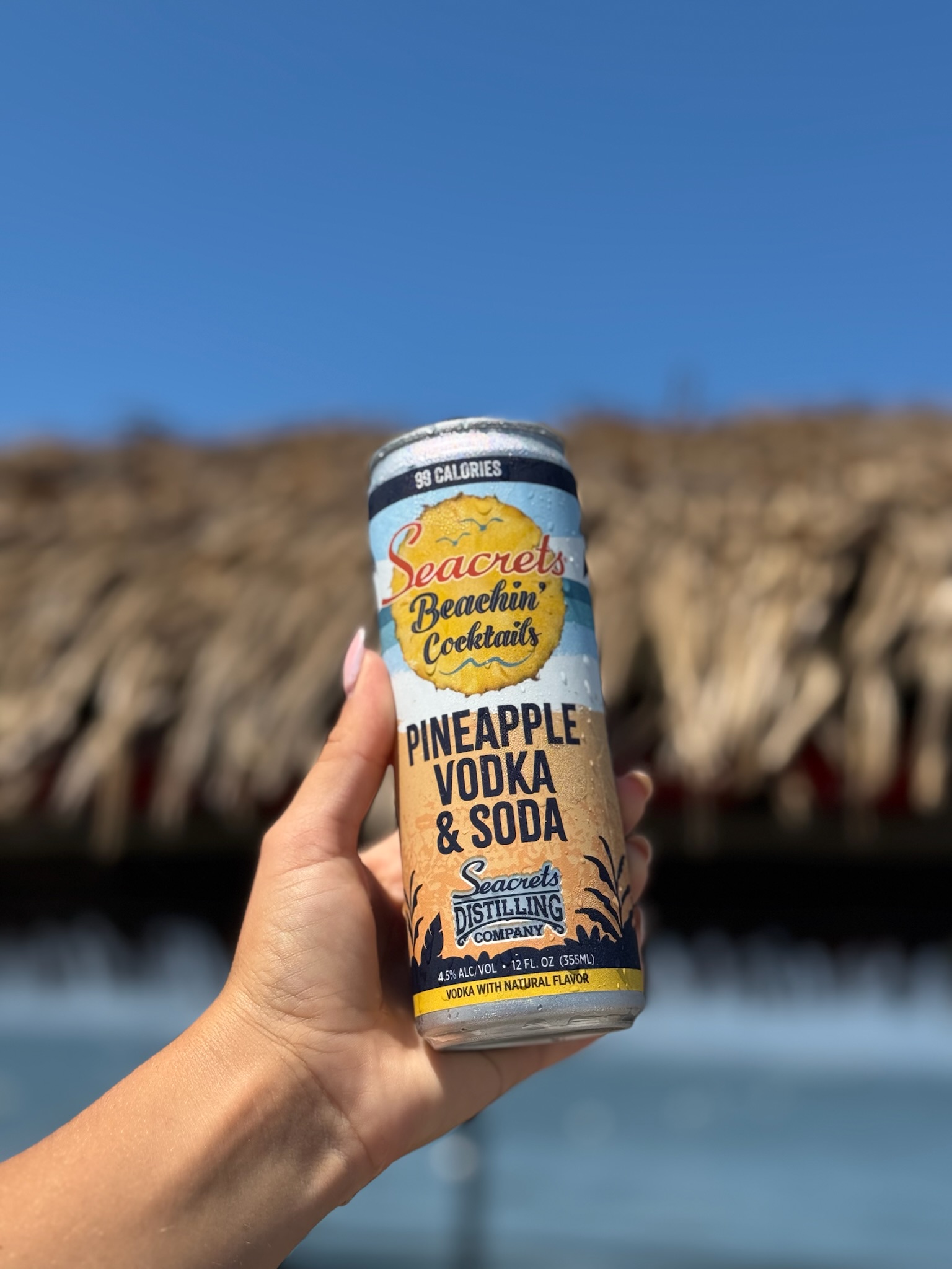a hand holding a can of pineapple and soda