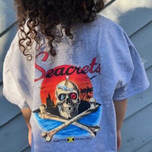 a little girl wearing a blue shirt with a pirate on it