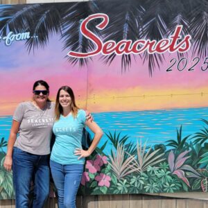 two women standing in front of a sign
