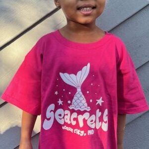 a little girl in a pink shirt standing on a deck