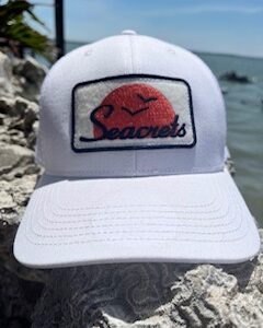 a white hat sitting on top of a rock near the ocean