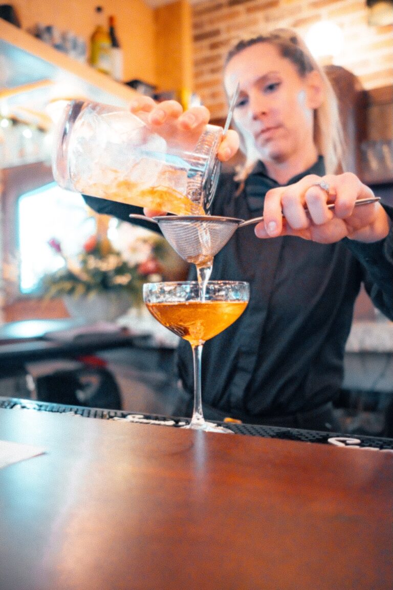 a woman pouring a drink into a martini glass