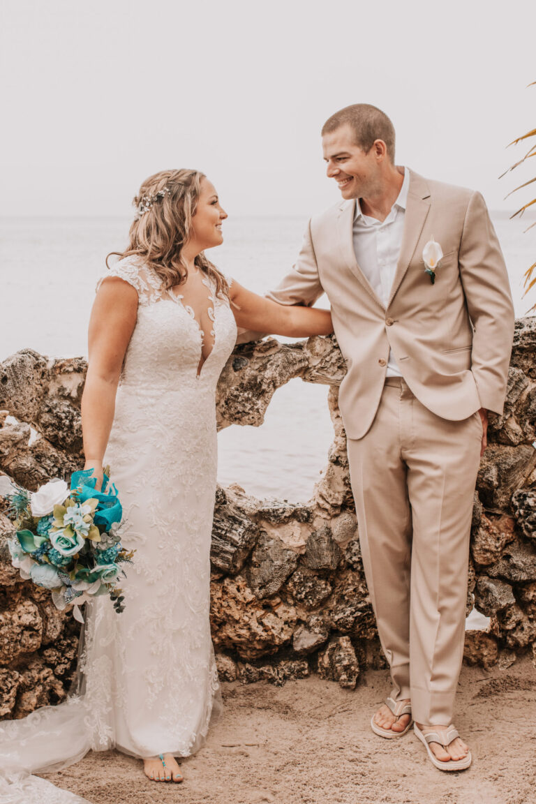 a bride and groom standing next to a stone wall