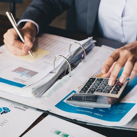 business man using calculator and writing on spreadsheets