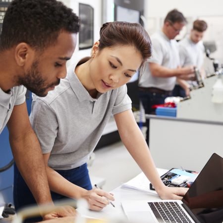 Two Engineers Using Programming Software On Laptop