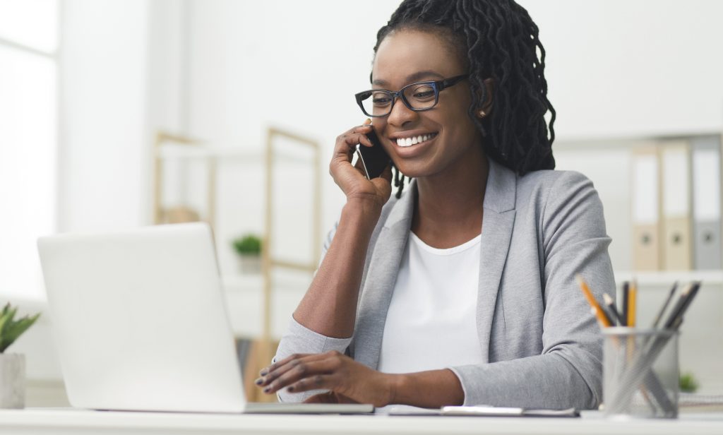 Happy Business Woman Having Phone Conversation Using Laptop In Office