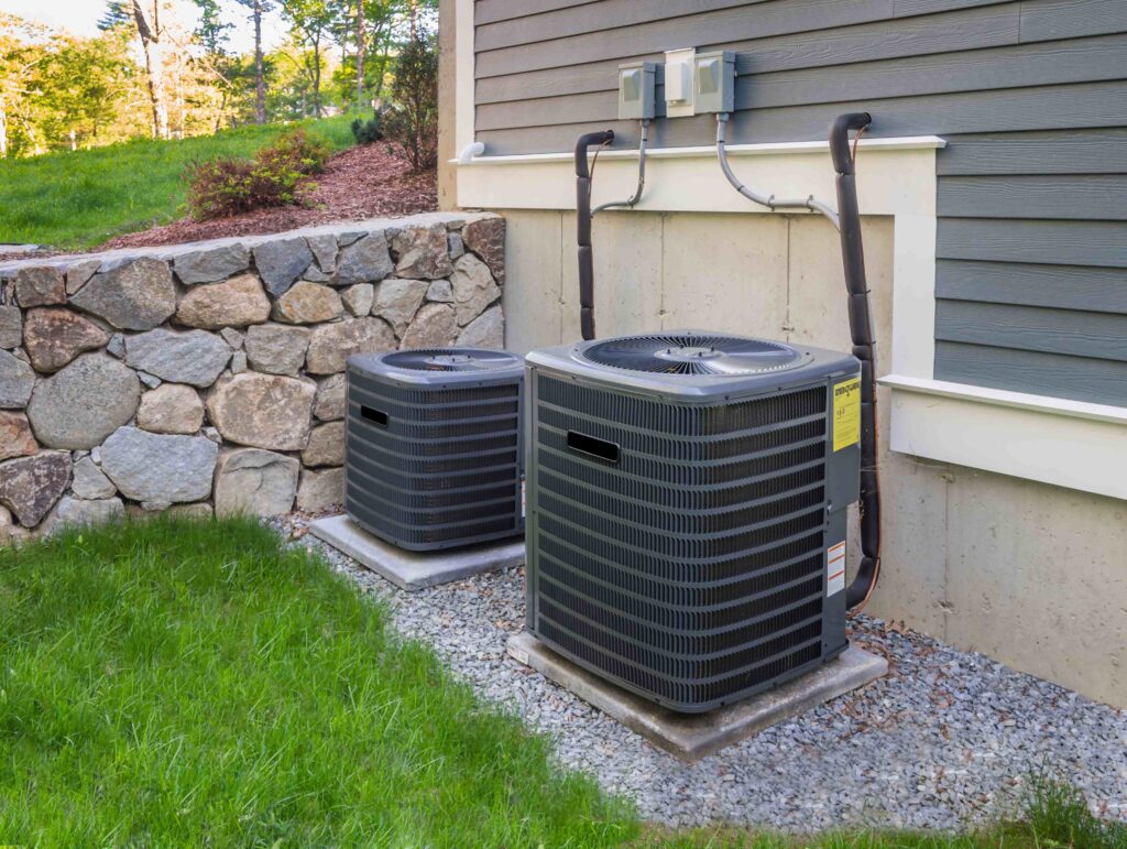 two air conditioners sitting on the side of a house