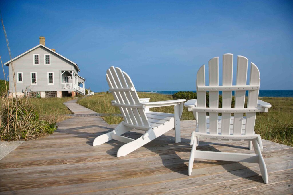 two white chairs sitting on top of a wooden deck