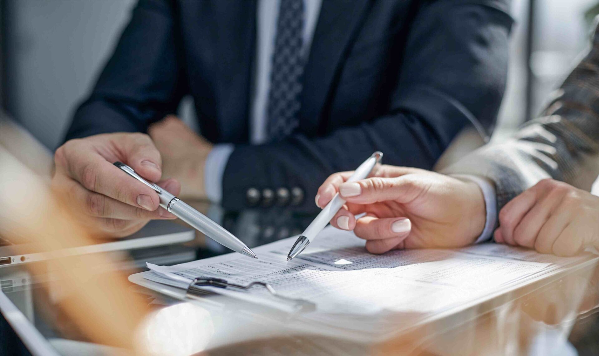 close up of hands holding pens pointing at document