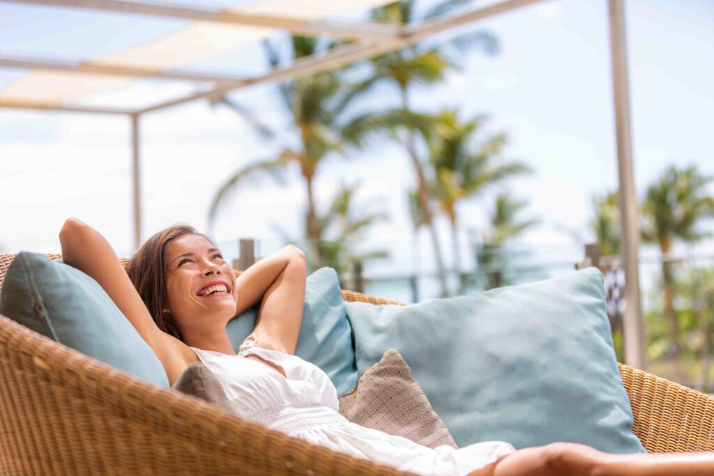 a woman laying in a wicker chair on the beach