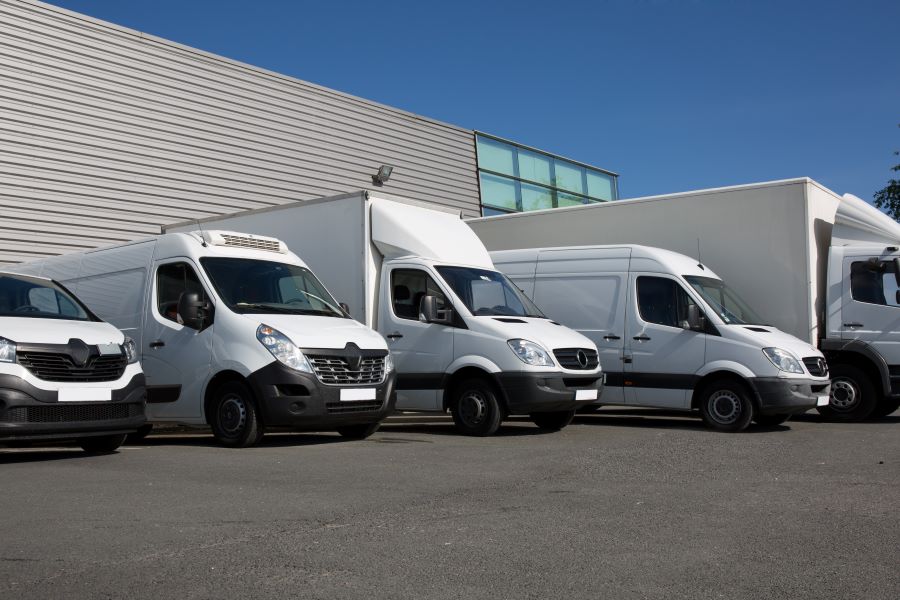 a row of white delivery trucks parked in front of a building