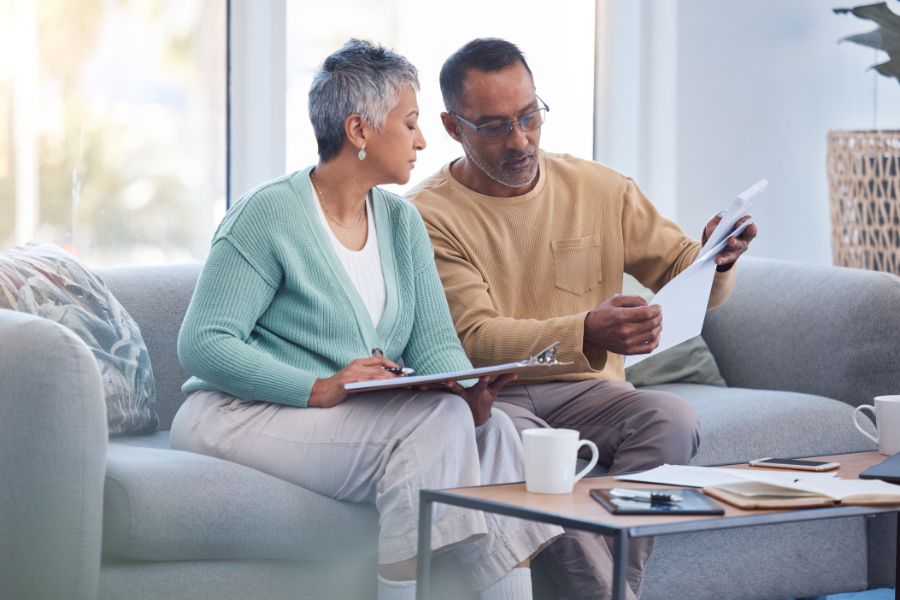 a man and woman sitting on a couch looking at papers