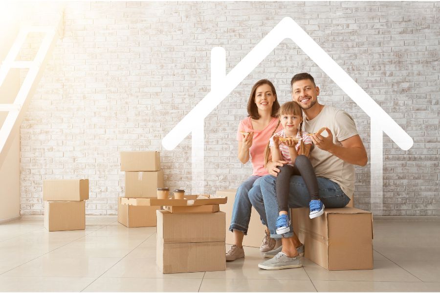 a family sitting on cardboard boxes in front of a house