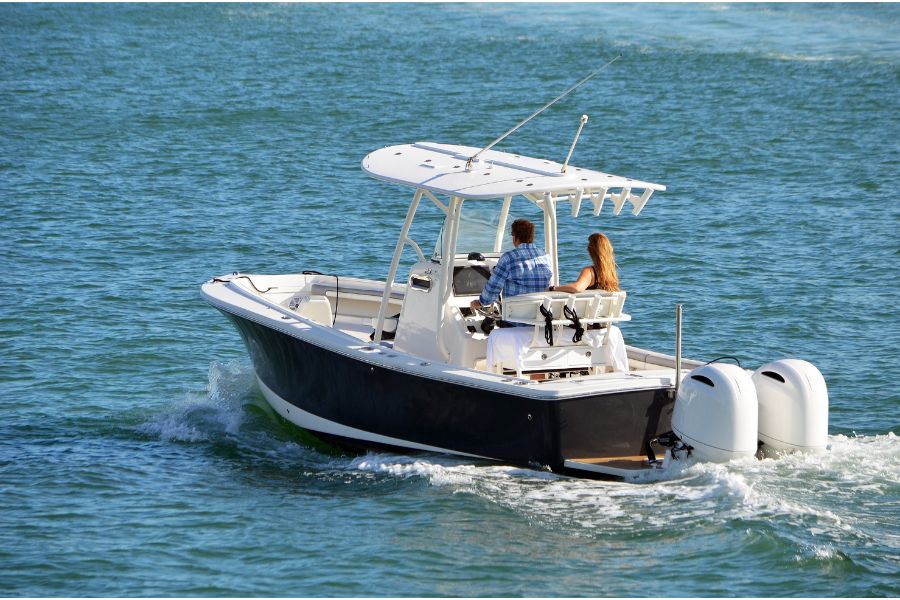 a man and woman riding on the back of a black and white boat